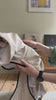 A video of a whippet wearing Strela Lightweight Reincoat in beige colour, showing putting the coat on and an outdoors beach walk