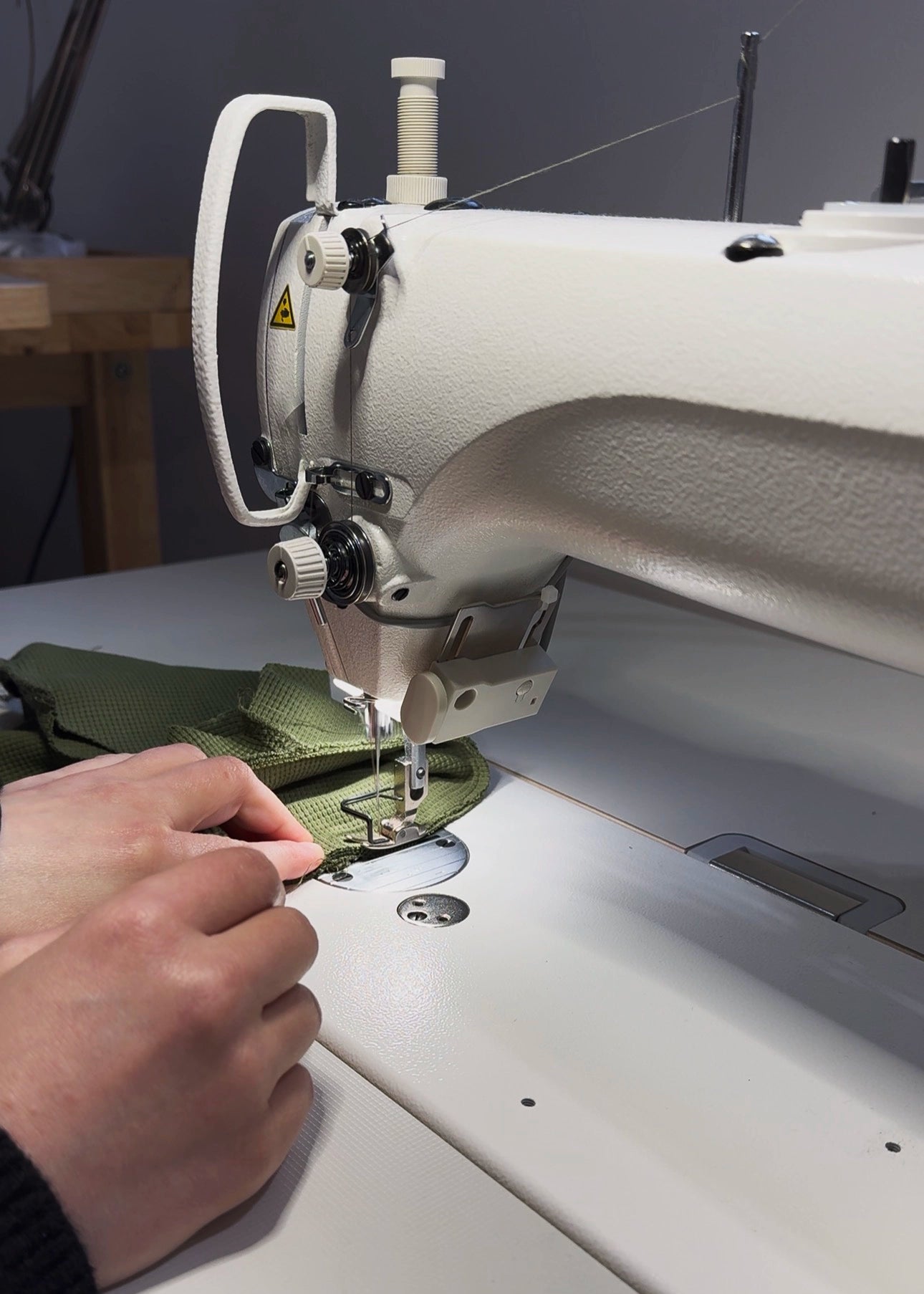 Sewing machine in use in Strela Studio London with a person's hand guiding fabric